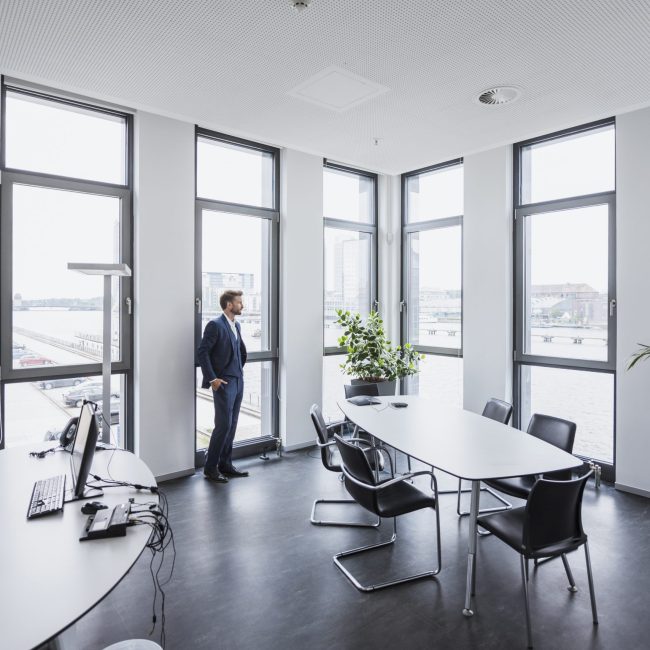 Businessman standing in his office looking out of the window